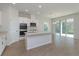 Open-concept kitchen with white cabinetry, stainless steel appliances, island, and adjacent dining area at 5025 Balsam Falls Rd, Deland, FL 32724