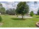Manicured backyard featuring a serene pond view, lush green grass, and mature trees at 5944 Hickey Way, The Villages, FL 32163