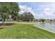 Backyard and pond with mature trees and nice landscaping on a sunny day at 5944 Hickey Way, The Villages, FL 32163