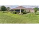 Spacious backyard with mature landscaping, a screened lanai, and lush green grass at 5944 Hickey Way, The Villages, FL 32163