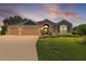 Beautiful exterior view of a landscaped home with a three-car garage at dusk at 5944 Hickey Way, The Villages, FL 32163