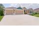 Exterior view of a well-maintained home featuring a three-car garage and manicured landscaping at 5944 Hickey Way, The Villages, FL 32163