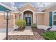Close up of home's front door, landscape, walkway, and front sidelight window with green shutters at 5944 Hickey Way, The Villages, FL 32163