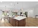 Kitchen island with pendant lights, undermount sink, and views of living and dining areas at 5944 Hickey Way, The Villages, FL 32163