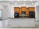 Kitchen island with wood cabinetry, black countertop, stainless sink, with view into living spaces beyond at 780 Mystic Hill Ct, Kissimmee, FL 34759
