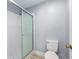 Shower and toilet inside bathroom with white tile and glass shower doors at 8608 Se 141St Street Rd, Summerfield, FL 34491