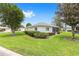 Well-maintained home featuring a lush green lawn, trimmed hedges, and mature trees in quiet community at 8608 Se 141St Street Rd, Summerfield, FL 34491