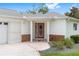 Inviting front entrance featuring a decorative red door, brick accents, and well-maintained landscaping at 8608 Se 141St Street Rd, Summerfield, FL 34491