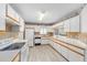 Bright kitchen features white appliances, white cabinets with tan trim, and wood-look floors at 8608 Se 141St Street Rd, Summerfield, FL 34491