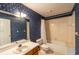 Bathroom with blue floral wallpaper, a bathtub and shower combination, and wood-trimmed vanity at 8705 Village Green Blvd, Clermont, FL 34711