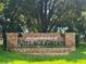 Townhomes of Village Green brick sign with lush green landscaping on a sunny day at 8705 Village Green Blvd, Clermont, FL 34711