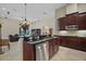 Modern kitchen featuring dark wood cabinets, stainless steel appliances, and a breakfast bar overlooking the living room at 926 Wood Briar Loop, Sanford, FL 32771