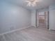 Bright bedroom with light gray wood flooring, a ceiling fan, and view into the kitchen at 1016 Eagles Lndg, Leesburg, FL 34748