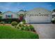 Charming single-story home featuring a red front door, brick driveway, and verdant landscaping at 1016 Eagles Lndg, Leesburg, FL 34748