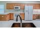 Well-lit kitchen features wood cabinets, white appliances, and stone countertops at 1016 Eagles Lndg, Leesburg, FL 34748