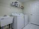 Functional laundry room featuring a utility sink, shelving, and washer/dryer hookups at 1016 Eagles Lndg, Leesburg, FL 34748