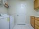 Convenient laundry room with oak cabinets, counter space, washer, dryer hookups, and white tile flooring at 1016 Eagles Lndg, Leesburg, FL 34748