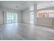 Spacious living room with light-colored wood floors, sliding glass doors to screened porch, and view of kitchen at 1016 Eagles Lndg, Leesburg, FL 34748