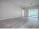 Spacious living room featuring wood-look flooring, neutral walls, a ceiling fan, and sliding glass doors at 1016 Eagles Lndg, Leesburg, FL 34748