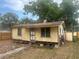 Small, rundown, single-story home with yellow siding, in need of renovation, with visible foundation issues at 102 Harold St, Leesburg, FL 34748