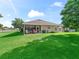 Manicured backyard featuring a covered patio, lush green grass and mature trees at 10986 Se 171St Street Rd, Summerfield, FL 34491