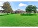 Well-maintained backyard featuring a covered patio, expansive green lawn, and mature shade trees at 10986 Se 171St Street Rd, Summerfield, FL 34491