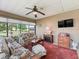 Relaxing lanai with ceiling fan, tv, and furniture offers views of the landscaped yard at 10986 Se 171St Street Rd, Summerfield, FL 34491