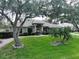 Charming one-story home featuring a well-manicured lawn and mature trees at 11036 Bronson Rd, Clermont, FL 34711