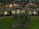 Charming single-story home featuring a well-manicured lawn and arched entryway, bathed in the warm glow of dusk at 11036 Bronson Rd, Clermont, FL 34711