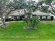 Charming home featuring lush green lawn, mature trees, and well-manicured landscaping at 11036 Bronson Rd, Clermont, FL 34711