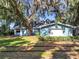 Charming blue home with lush lawn, mature trees with Spanish Moss, and train tracks in the yard at 1107 Northshore Dr, Eustis, FL 32726