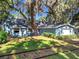 Charming blue home with lush lawn, mature trees with Spanish Moss, and train tracks in the yard at 1107 Northshore Dr, Eustis, FL 32726