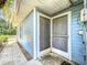 Exterior view of the front entrance with blue siding, screen doors, and a paved walkway at 1107 Northshore Dr, Eustis, FL 32726