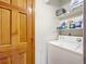 Functional laundry room featuring a white washing machine, wooden door, and storage shelving at 1107 Northshore Dr, Eustis, FL 32726