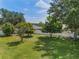 Large backyard with mature trees, green grass, and a white fence in the background at 11437 Alameda Sandra Dr, Clermont, FL 34711