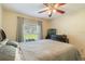 A comfortably furnished bedroom features a ceiling fan and a window with curtains at 11437 Alameda Sandra Dr, Clermont, FL 34711
