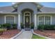 Up close exterior shot of an inviting doorway framed by pillars and manicured shrubbery, creating a welcoming entrance at 11437 Alameda Sandra Dr, Clermont, FL 34711