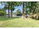 Expansive green backyard with mature trees, partial fence, and a screened porch, perfect for outdoor activities at 121 Mason Park Dr, Daytona Beach, FL 32117