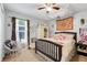 Bright bedroom with a ceiling fan, a large window with sheer curtains, and decorative tapestry at 1311 Rain Forest Ln, Minneola, FL 34715