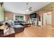 Cozy living room with a plush leather sectional, complemented by hardwood floors, a ceiling fan, and bright windows at 1311 Rain Forest Ln, Minneola, FL 34715