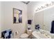 Neat powder room offering a pedestal sink, decorative mirror, and elegant wallpaper at 13165 Se 93Rd Cir, Summerfield, FL 34491