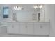 Bathroom with dual vanities, a large mirror, and elegant lighting fixtures providing a bright and airy atmosphere at 14249 Crest Palm Ave, Windermere, FL 34786