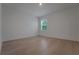 A brightly lit bedroom offers light-colored wood floors, white walls, and a window with natural views at 14249 Crest Palm Ave, Windermere, FL 34786