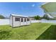 View of the backyard shed with white fence and well-manicured lawn at 15022 Se 94Th Ct, Summerfield, FL 34491