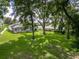 A large backyard featuring mature trees, lush green lawn, a screened-in pool and the home's back porch at 16951 Florence View Dr, Montverde, FL 34756