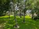 Large backyard featuring mature trees, lush green lawn, and a view of the home's back porch and screened pool at 16951 Florence View Dr, Montverde, FL 34756