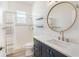 Clean and modern bathroom featuring a round mirror, black vanity, and shower with gray and white curtains at 16951 Florence View Dr, Montverde, FL 34756