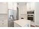 Kitchen features stainless steel refrigerator and oven with white cabinetry, and an island with matching countertops at 16951 Florence View Dr, Montverde, FL 34756