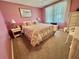 Cozy bedroom featuring floral bedding, plush carpet, and a bright window for natural light at 175 Hibiscus Way, Leesburg, FL 34748