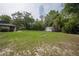 Spacious backyard featuring mature trees, a storage shed, and lush green grass at 18015 Palm St, Umatilla, FL 32784